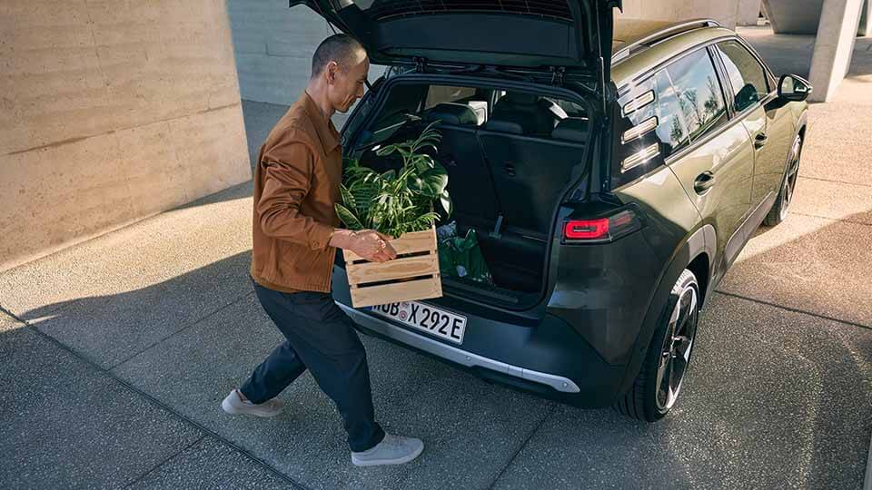Volkswagen ID. Cross, grün, Heckansicht, ein Mann belädt den Kofferraum