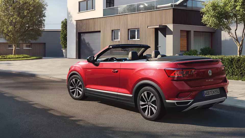 Volkswagen T-Roc Cabriolet ENERGY, rot, Heck-Seitenansicht, parkend auf Straße, moderne Architektur im Hintergrund