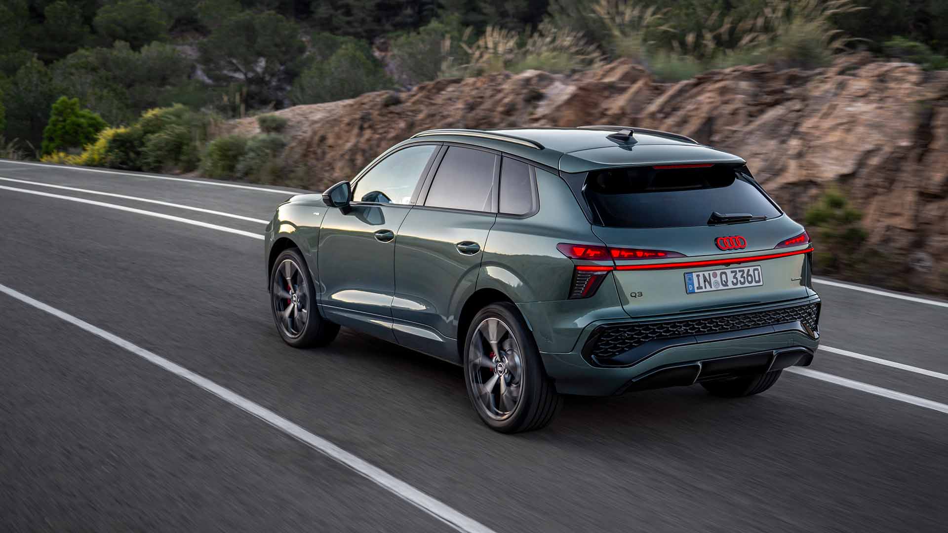 Audi Q3 SUV, grün, Heck-Seitenansicht, fahrend auf Landstraße