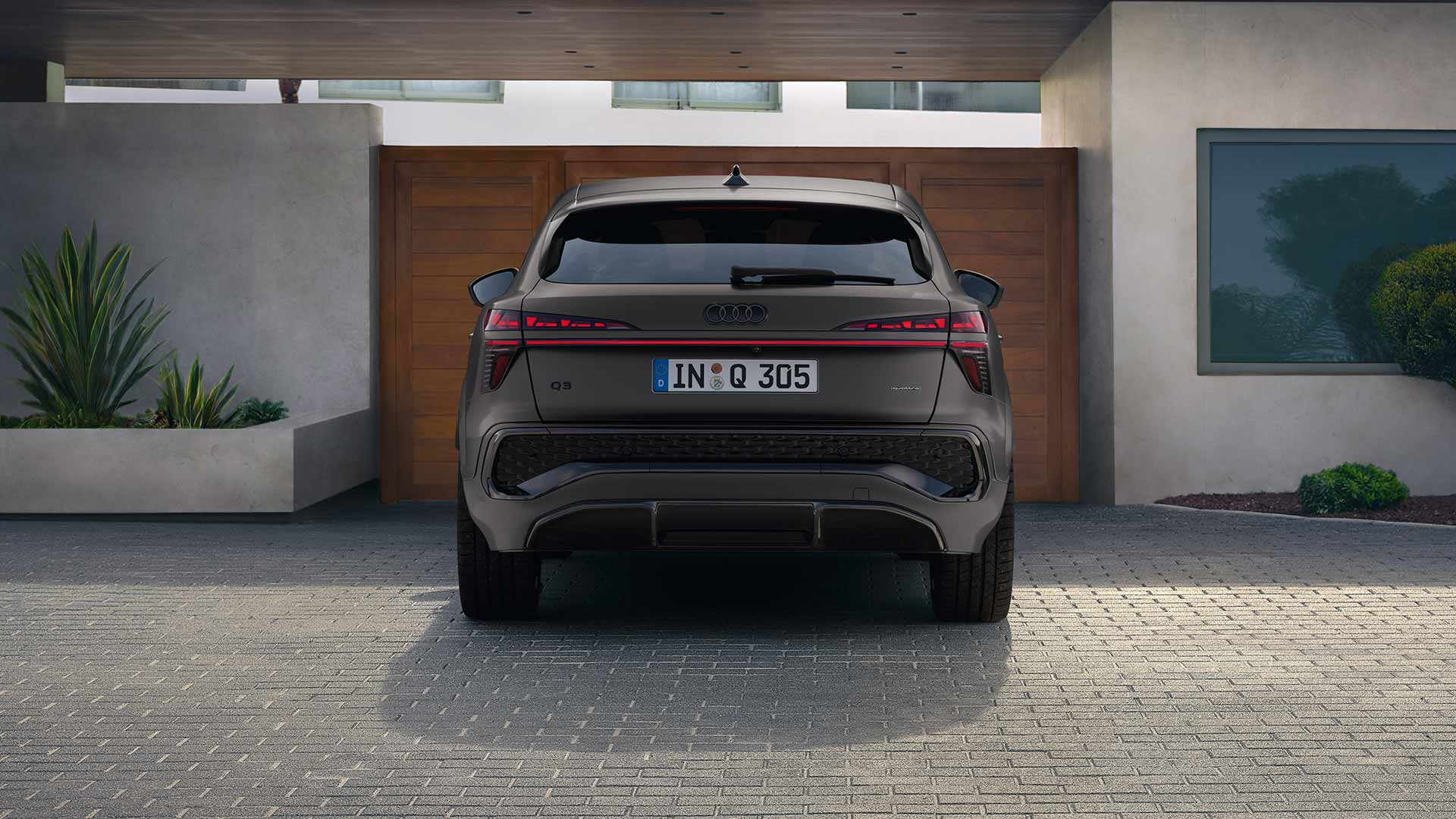 Audi Q3 Sportback, schwarz-matt, Heckansicht, parkend vor Tor