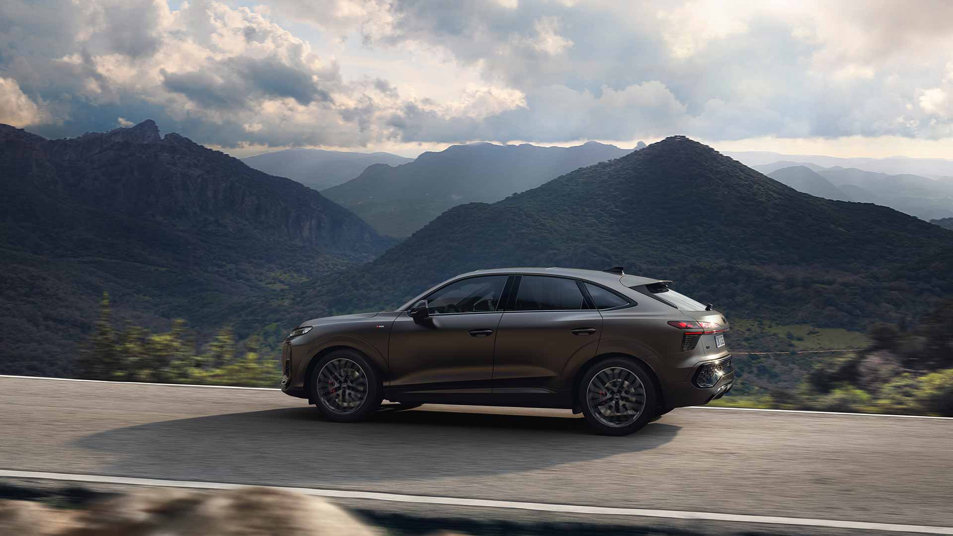 Audi Q3 Sportback, schwarz-matt, Seitenansicht, fahrend vor Bergpanorama