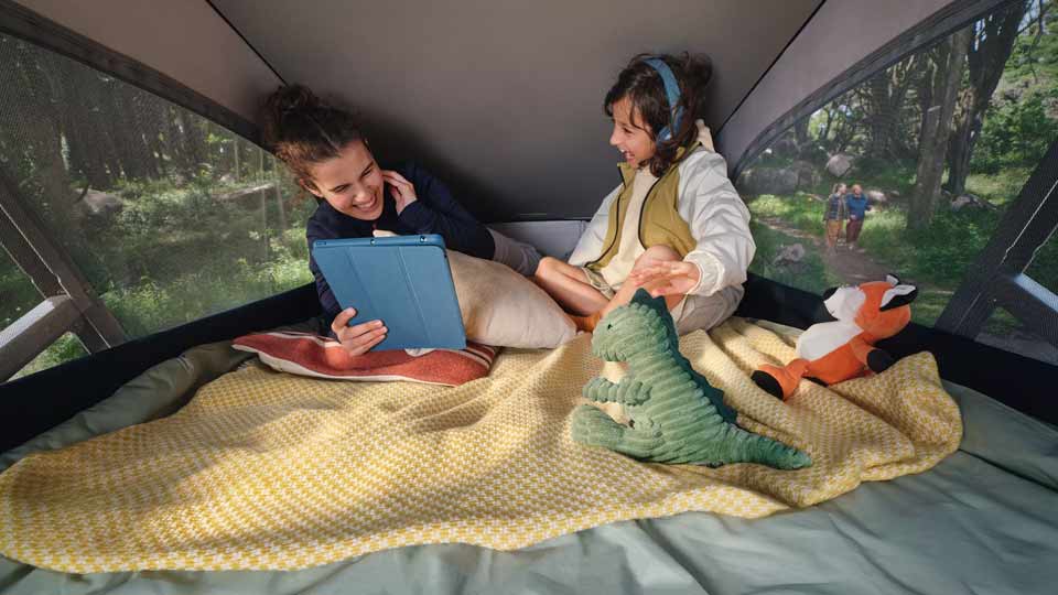 Zwei junge Menschen haben Spaß und lachen im Aufstelldach des VW California