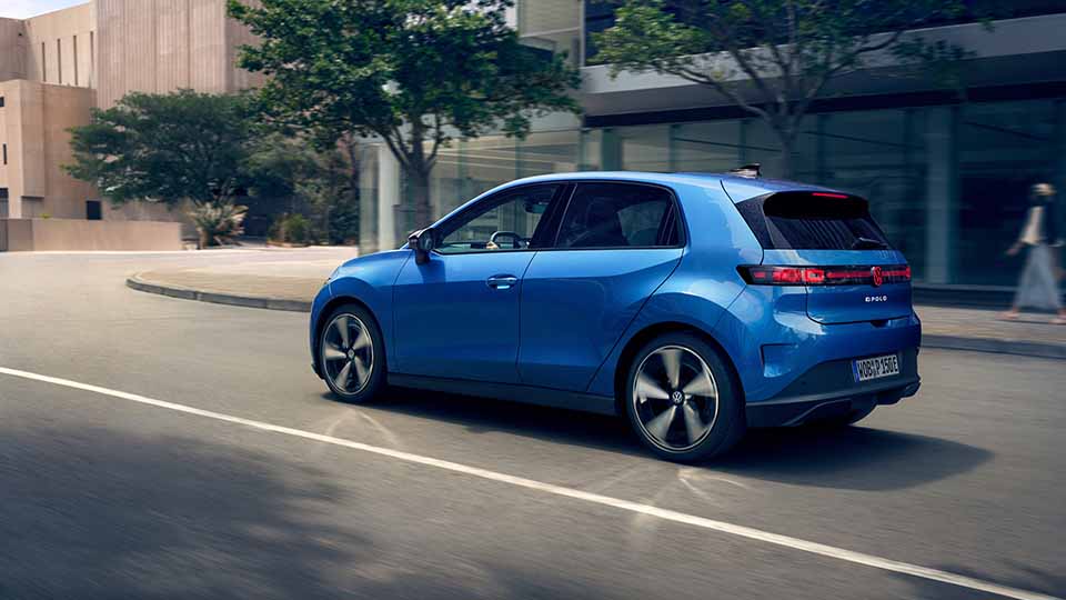 Volkswagen ID. Polo, blau, Heckansicht, dynamisch auf einer Straße fahrend